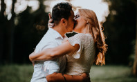 Casal de homem branco com camisa branca e mulher loira com camisola bege se beijando e sentindo apetite sexual excessivo.