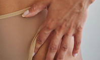 Mão de mulher em cima de calcinha cor de pele.