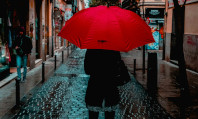 Mulher na rua segurando guarda-chuva vermelho no Dia pelo Vim da Violência contra Profissionais do Sexo.