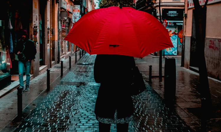 Mulher na rua segurando guarda-chuva vermelho no Dia pelo Vim da Violência contra Profissionais do Sexo.