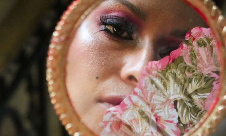 Rosto de mulher maquilhada num espelho, com um tecido em tons rosa e verdes a tapar metade, enquanto pensa em usar estimulante sexual feminino.