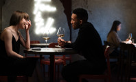 Homem com camisola preta e mulher com vestido preto conversando numa mesa em torno de perguntas pesadas para o crush.
