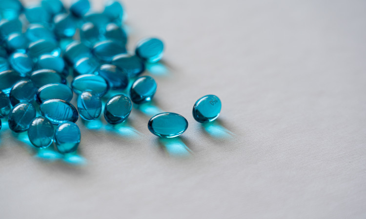 Comprimidos azuis espalhados em fundo cinzento em experiência sobre quem não pode tomar Viagra.