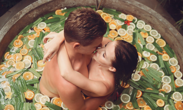 Casal numa banheira com frutas coloridas antes de sexo com óleo.