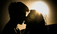 Casal de homem e mulher se beijando na penumbra, com luz no horizonte, se preparando para sexo zen.