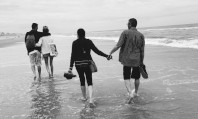Fotografia a preto e branco de dois casais caminhando na praia de mão dada após sonhar com troca de casais. 