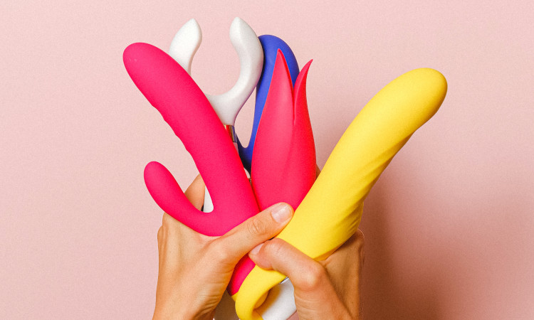 Mãos segurando brinquedos sexuais de várias cores para treinamento anal.