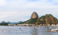 Imagem do Rio de Janeiro, destino de turismo sexual no Brasil, com barcos no mar e a encosta verde da montanha.