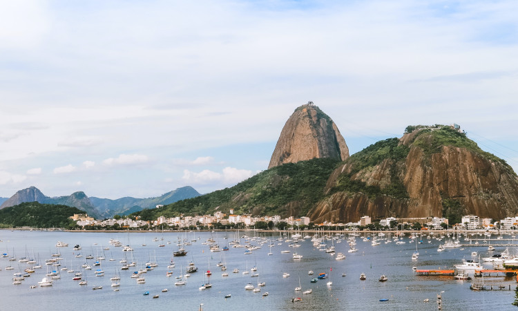 Imagem do Rio de Janeiro, destino de turismo sexual no Brasil, com barcos no mar e a encosta verde da montanha.